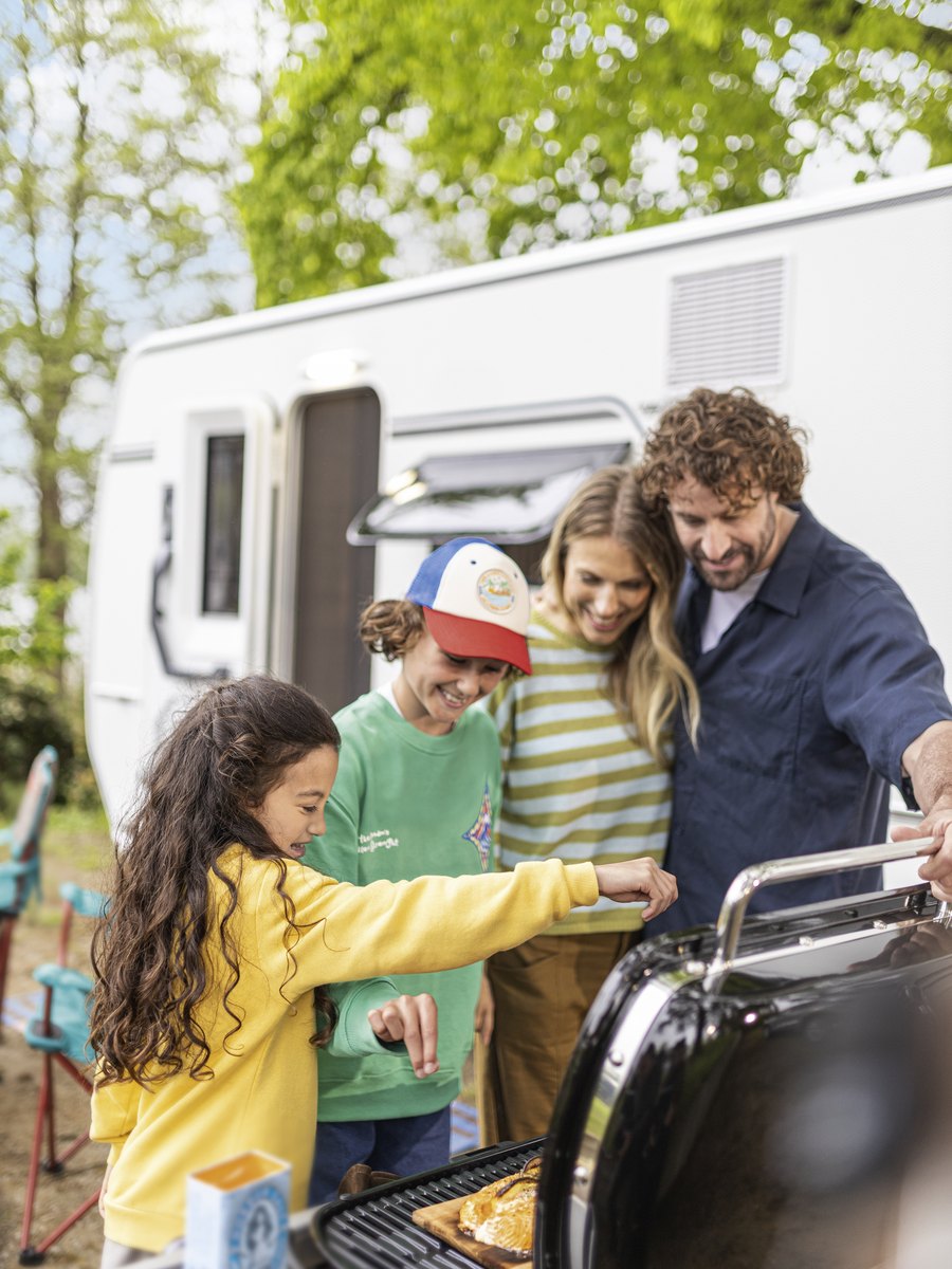 Familie beim Grillen vor einem Fendt-Caravan BIANCO